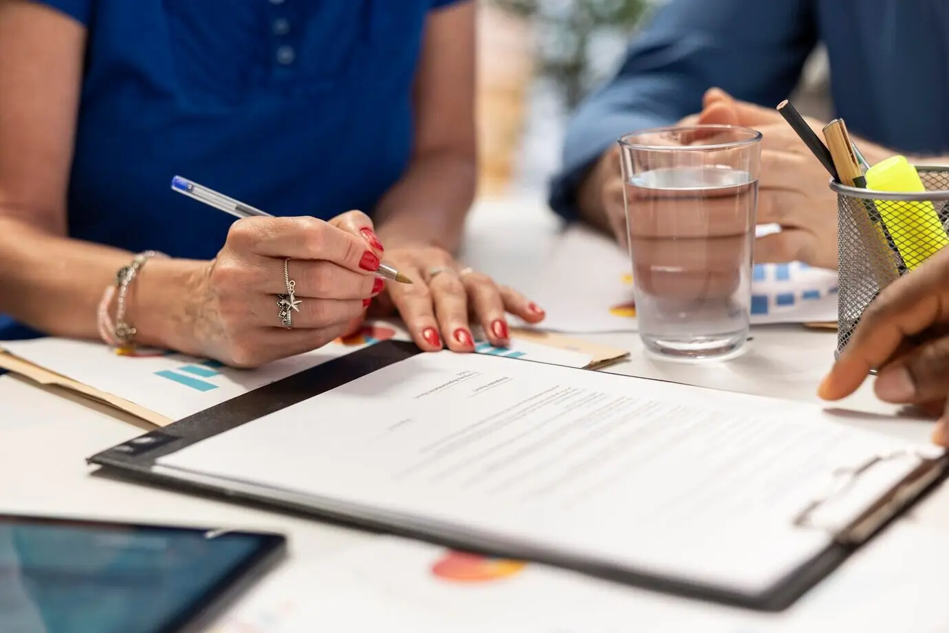 На встрече пожилая женщина подписывает новый договор пенсионного плана.